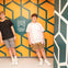 Two individuals standing in front of an optical illusion wall at the Museum of Illusions Denver, appearing tilted.