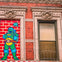 Brick building with ornate window frames. Left frame has a "Teenage Mutant Ninja Turtle" mosaic; right window has a metal grate.