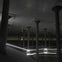 A dimly lit underground structure with concrete columns, reflective water, and illuminated lines creating a modern aesthetic.
