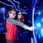 Two people smiling and pointing at a glowing interactive display with blue neon lights and jellyfish graphics in a dark room.