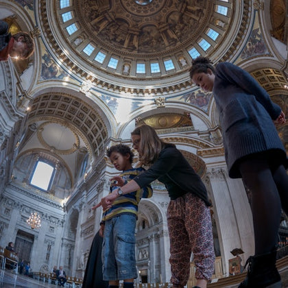 A group of people standing inside a large ornate building with a decorated dome ceiling and intricate architectural details.