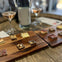 Small dessert squares arranged on wooden boards, accompanied by two glasses of rosé and a bottle on a wooden table.