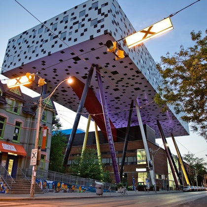 A unique building with a pixelated design elevated on colorful stilts, surrounded by urban street elements.