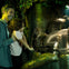 A man and child smile at a woman inside a small, transparent enclosure surrounded by plants and greenery.