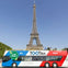 A double-decker tour bus with 'Planet Friendly' and 'TOOTBus Paris' branding in front of the Eiffel Tower.
