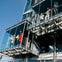 People standing on modern glass balconies attached to a building, with a clear blue sky in the background.