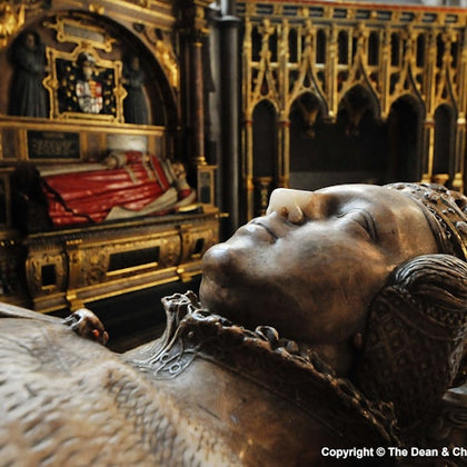 Close-up of a detailed stone effigy of a reclining figure in a medieval setting, with ornate gilded background and a resting knight effigy.