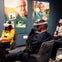 People seated in a room wearing virtual reality headsets, with large portraits displayed on the wall behind them.