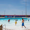 People enjoying a wave pool at a water park under a clear blue sky.