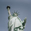 The Statue of Liberty holding a torch in her raised right hand and a tablet in her left hand, against a clear sky.