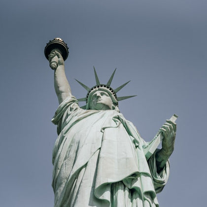 The Statue of Liberty holding a torch in her raised right hand and a tablet in her left hand, against a clear sky.