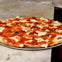 A freshly baked pepperoni pizza on a plate, placed on a marble countertop.