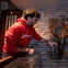 A person in a red hoodie interacts with a large lobster sculpture mounted on a wooden plaque, set against a brick wall.