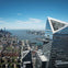 A modern skyscraper with a triangular rooftop observatory overlooking a cityscape and river under a clear blue sky.