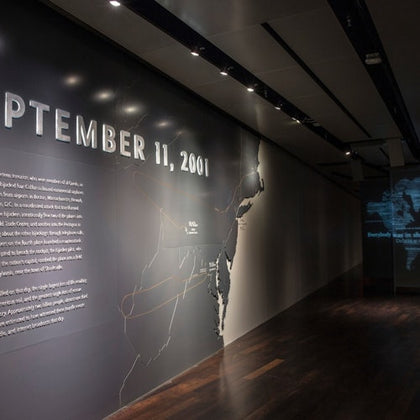 A museum exhibit wall displaying the text "September 11, 2001" with a map and informational text lit by spotlights.