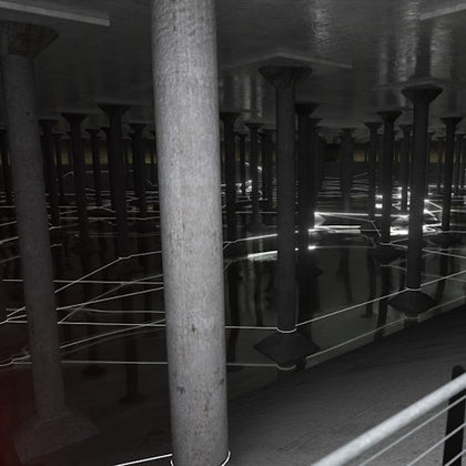A dimly lit underground space with numerous stone columns reflected on a shallow water surface, illuminated by linear lights.