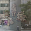 Abstract graffiti-style art displayed on a glass building facade with city reflections and passing cars.