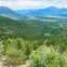 A scenic view of a lush green valley surrounded by forested mountains under a partly cloudy sky.