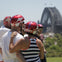 A group of people wearing red helmets with a view of the Sydney Harbour Bridge in the background on a sunny day.