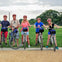 Five people wearing helmets stand with their bicycles on a path in a park, with the Washington Monument visible in the background.