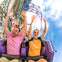 Three people on a large inflatable raft splashing in a water ride under a sign that reads 'Big Kahuna.'