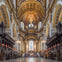 Interior of a grand cathedral with ornate arches, stained glass windows, and a gilded altar under a domed ceiling.