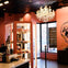 A cozy donut shop with pink walls, pastry display case, chandelier, and a large donut-themed mural near the window.