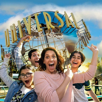 A family of four enthusiastically posing in front of the iconic Universal Studios globe.