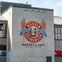 Boudin Sourdough Bakery & Cafe logo painted on a building wall, featuring wheat stalks, text, and a large "B" emblem.