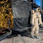 A space suit-clad mannequin stands near a replica of a lunar module, surrounded by simulated lunar surface materials.