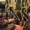 A modern lobby with a large mural of walking figures, leather seating, cushions, floor lamps, and suitcases on the floor.