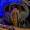 A decorative display featuring a white carriage resembling a pumpkin with a human-like figure and caution tape in the foreground.