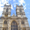 The facade of a large Gothic-style cathedral with tall twin towers and detailed architecture under a blue sky.