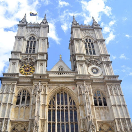The facade of a large Gothic-style cathedral with tall twin towers and detailed architecture under a blue sky.