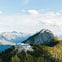 Building on a forested mountain surrounded by distant peaks under a partly cloudy sky.