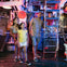 A family of four exploring an industrial-themed environment, with pipes and gauges, and a ladder being climbed by a child.