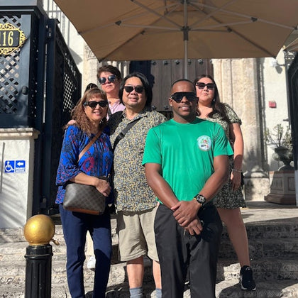 A tour guide poses with a group in front of the Versace Mansion.
