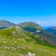 A scenic view of green rolling hills and distant mountains under a clear blue sky.