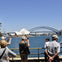 The bus tour group at Mrs Macquaries Point. Tourists are taking pictures of the Sydney Opera House and the Harbour Bridge.
