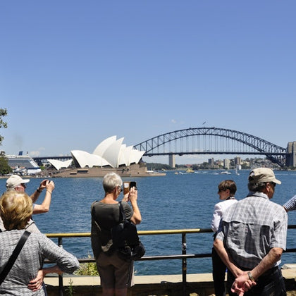 The bus tour group at Mrs Macquaries Point. Tourists are taking pictures of the Sydney Opera House and the Harbour Bridge.