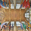 Ornate cathedral ceiling with intricate designs and large stained glass windows, adorned with colorful banners.