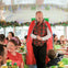 A festive scene inside a decorated bus with people enjoying food and a man in a red cape interacting with them.