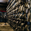 Rows of metal helmets and armor displayed on stands in a dimly lit room, with a glass display case in the background.