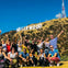 A group of people posing in front of the Hollywood sign on a sunny day with a clear blue sky.