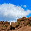 Rocky terrain with large boulders under a clear blue sky with a few white clouds.