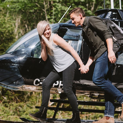 A couple holding hands, walking in front of a helicopter