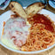 A plate of spaghetti with marinara sauce, a piece of chicken Parmesan topped with melted cheese, and two slices of bread.