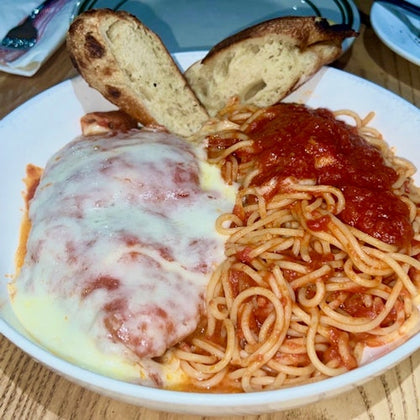 A plate of spaghetti with marinara sauce, a piece of chicken Parmesan topped with melted cheese, and two slices of bread.