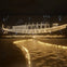 A glowing golden outline of a traditional boat displayed against a dark background, with symbols and a lit path in the foreground.
