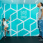 Two people in a geometric room at the Museum of Illusions New York, creating an optical illusion of size difference.